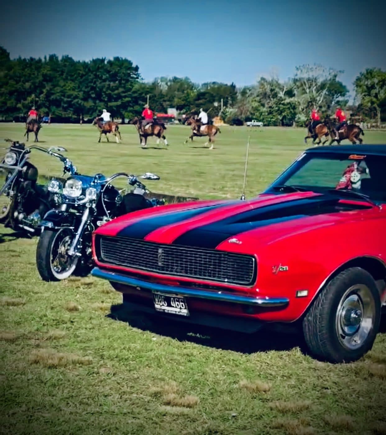Un Camaro rojo con franjas negras y las motos alineadas al lado
