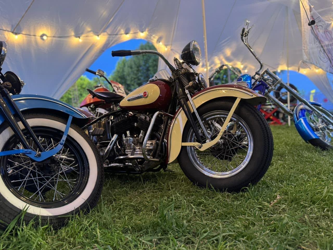 Una Harley clásica crema bajo las luces de la carpa