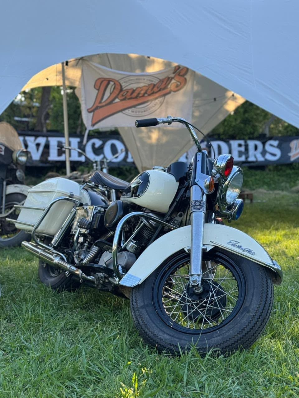 Una moto blanca clásica bajo el cartel Welcome Riders