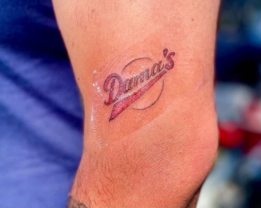 El logo de Dama's tatuado en un brazo
